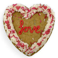 Gluten-free, dairy-free heart-shaped cookie cake with buttercream frosting, festive sprinkles, and a piped “love” message.
