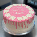 Strawberry cake with vanilla buttercream, pink drip icing, and floral decorations